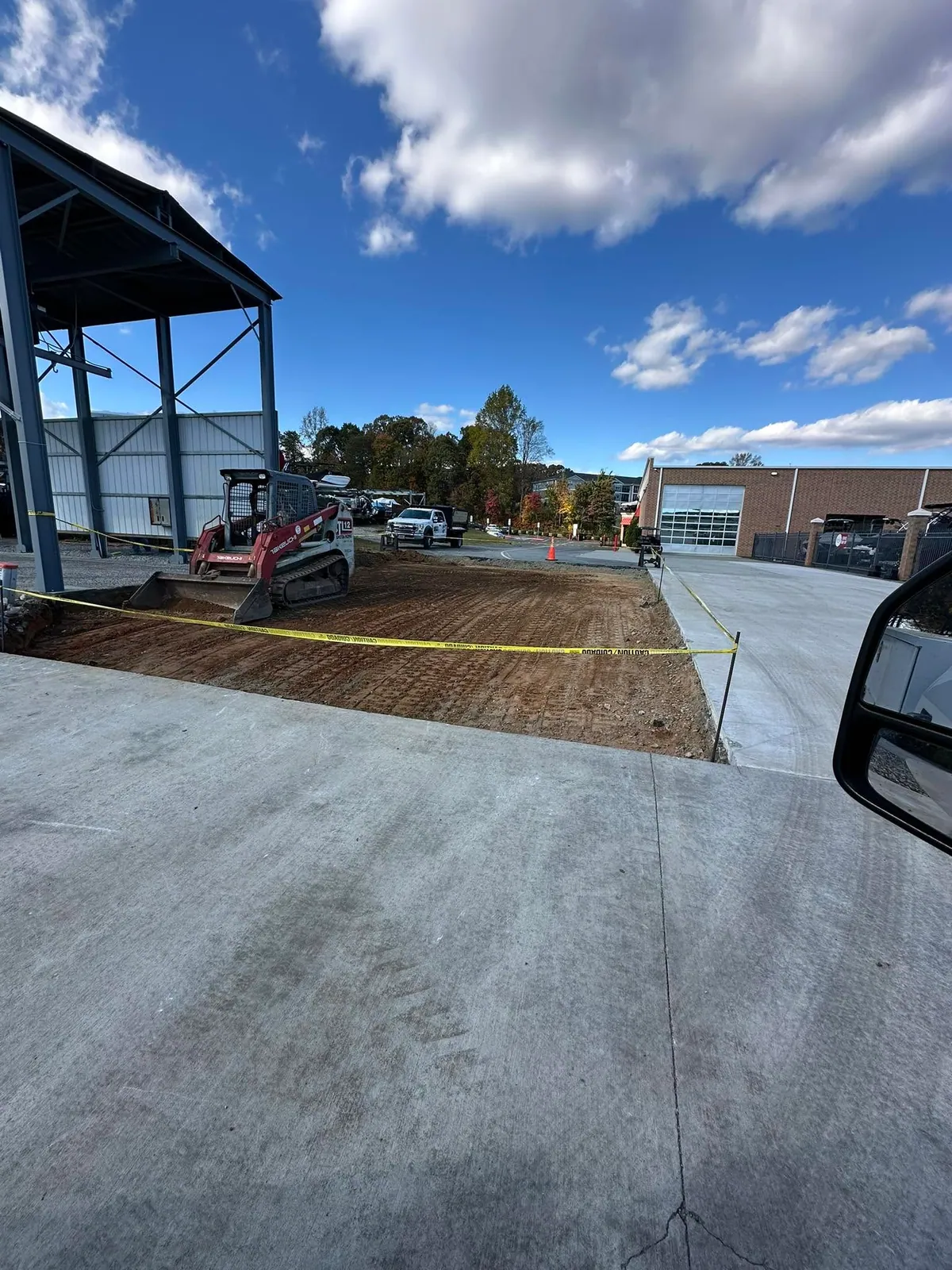 Takeuchi TL12 on prepped subgrade under steel canopy awaiting concrete pour at boat dealership