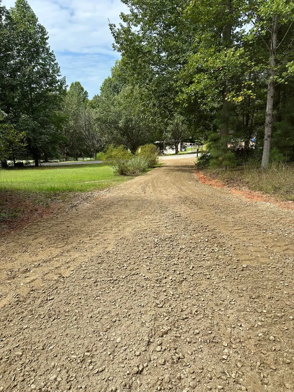 Finished crusher-run gravel driveway graded through wooded lot toward road