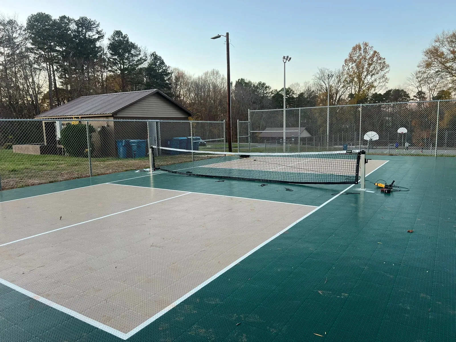 Finished pickleball courts with green and tan tile surface and nets inside chain-link fence at park in Claremont, NC