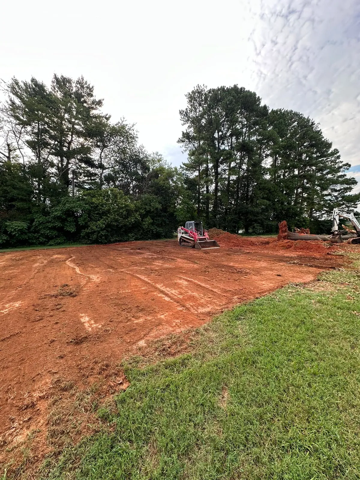 Takeuchi track loader cutting 60x60 red clay pad for pickleball courts, mini excavator pulling stump in Claremont, NC