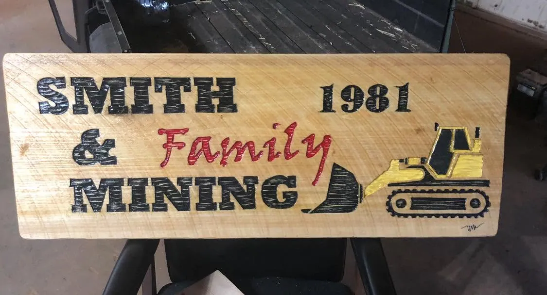 Carved wooden sign reading Smith & Family Mining 1981 with painted dozer, on UTV bed